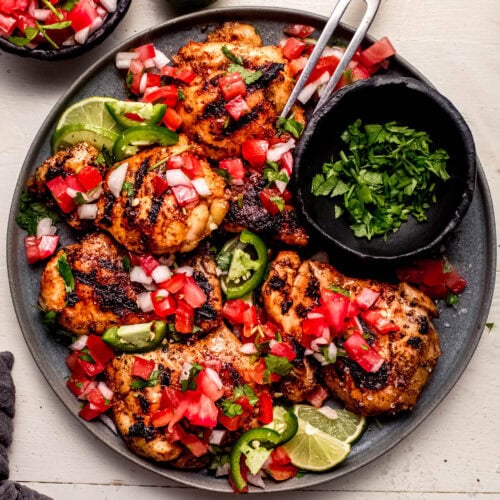 Overhead shot of pico de gallo chicken on grey plate next to small bowl of cilantro.