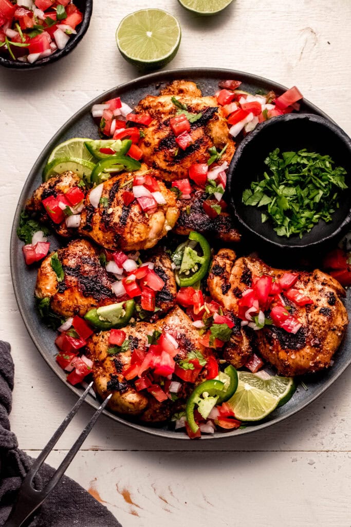 Overhead shot of pico de gallo chicken on grey plate next to small bowl of cilantro.