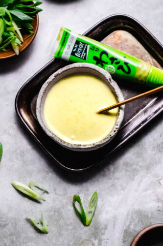Bowl of wasabi mayo next to small tube of wasabi sauce.