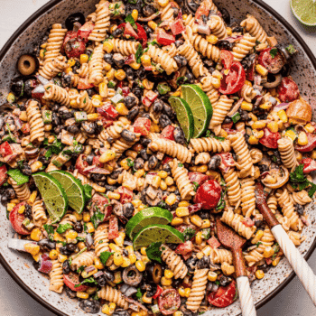 Mexican pasta salad in serving bowl with tongs.