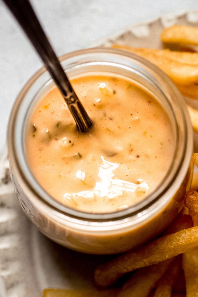 Overhead shot of Smashburger sauce in small glass jar with spoon.