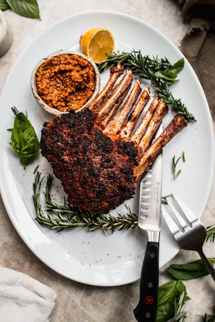 Finished sun dried tomato crusted rack of lamb on serving platter before slicing.