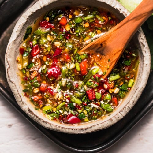 Overhead close up of crying tiger sauce in bowl with wooden spoon.