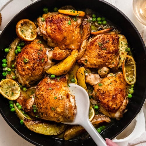 Overhead shot of finished chicken vesuvio in skillet with serving spoon.