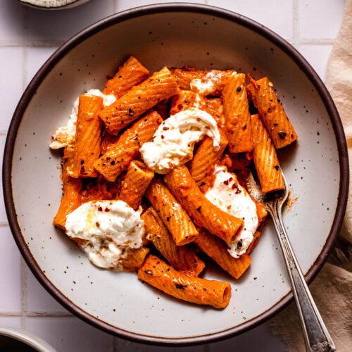 Smoky tomato pasta with burrata cheese in serving bowl with fork.
