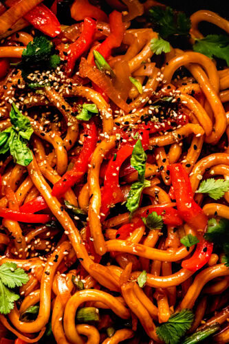 Spicy gochujang noodles served in a black bowl with chopsticks, photographed from above.