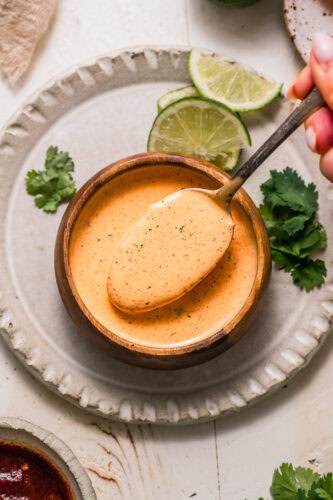 Overhead shot of spoon dipping into small bowl of chipotle ranch sauce.