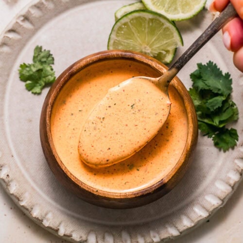 Overhead shot of spoon dipping into small bowl of chipotle ranch sauce.