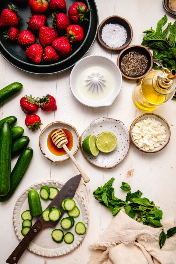 Ingredients for strawberry cucumber salad on counter.