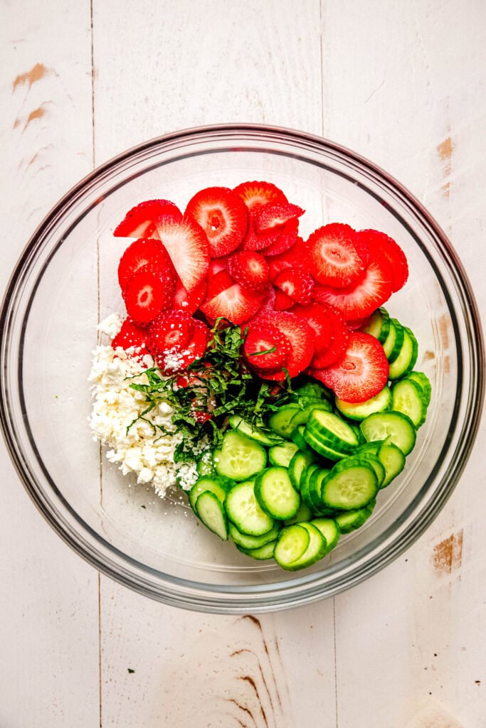 Ingredients for strawberry cucumber salad in bowl before combining.