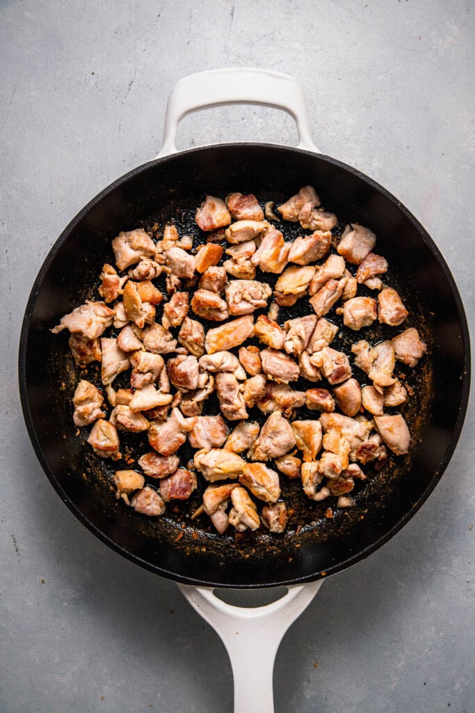 Chicken pieces cooking in skillet.