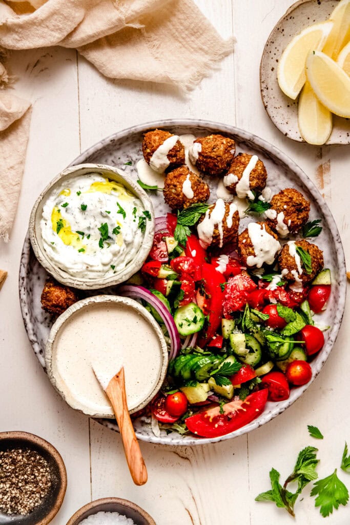 Finished chicken shawarma meatballs on plate with tzatziki sauce and tahini sauce.