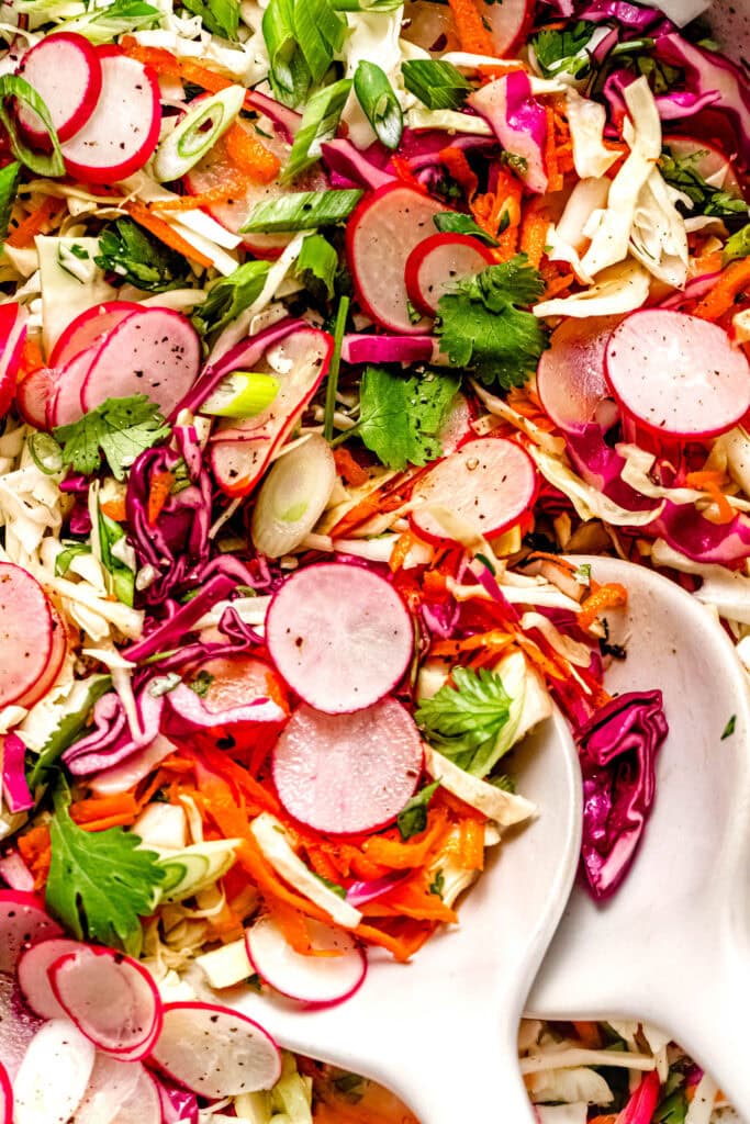 Overhead close up of finished radish slaw with serving tongs.