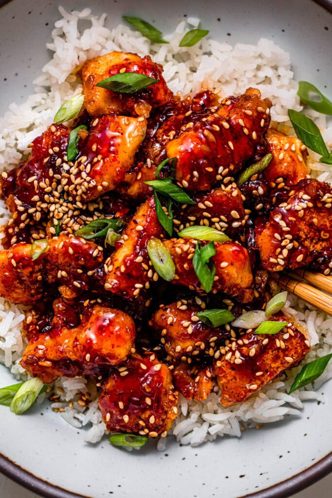 Overhead close up of sweet chili chicken served on bed of rice.