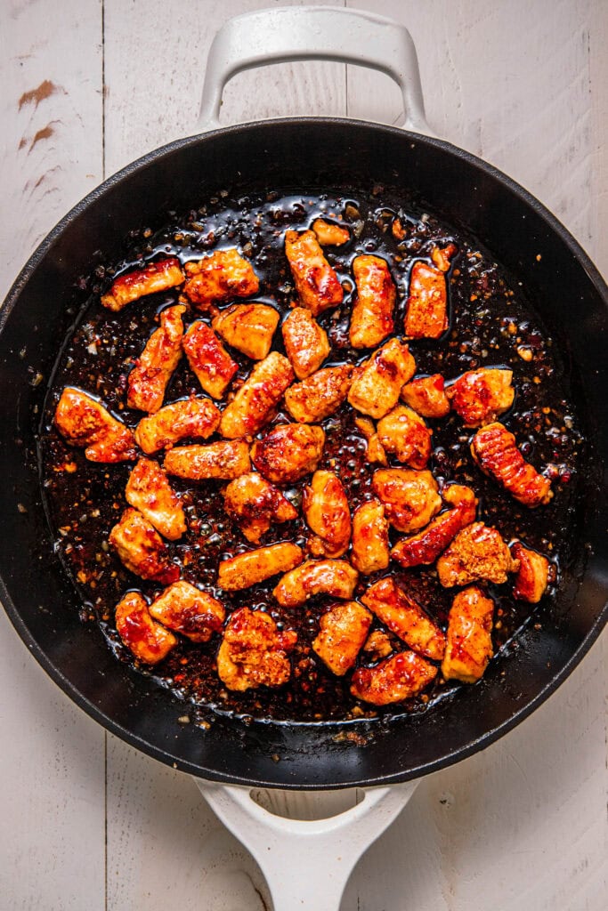 Chicken pieces being tossed with sweet chili sauce.