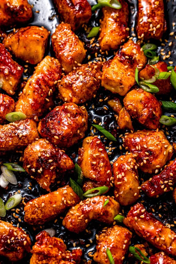 Overhead close up of sweet chili chicken sprinkled with green onions and sesame seeds.