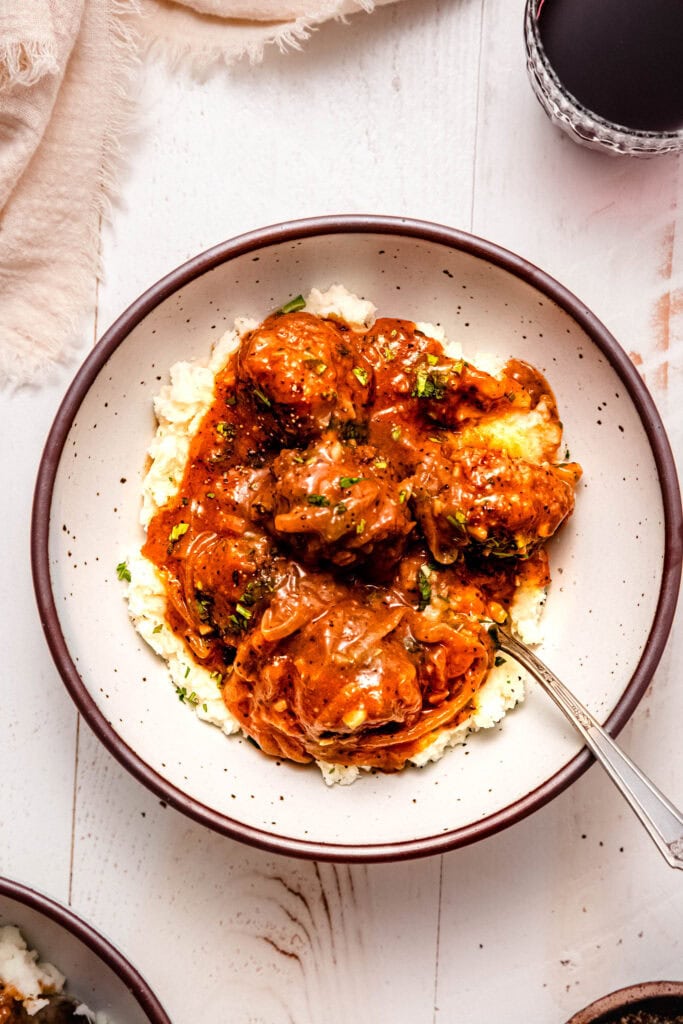 Finished salisbury steak meatballs in bowl with mashed potatoes.