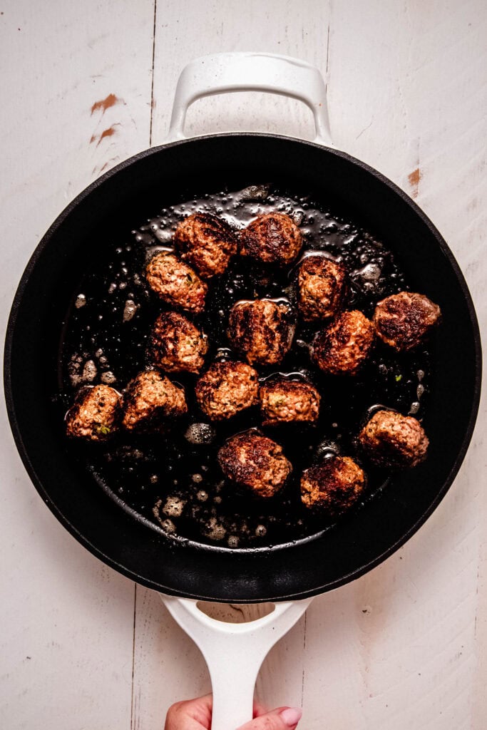 Meatballs browning on skillet.