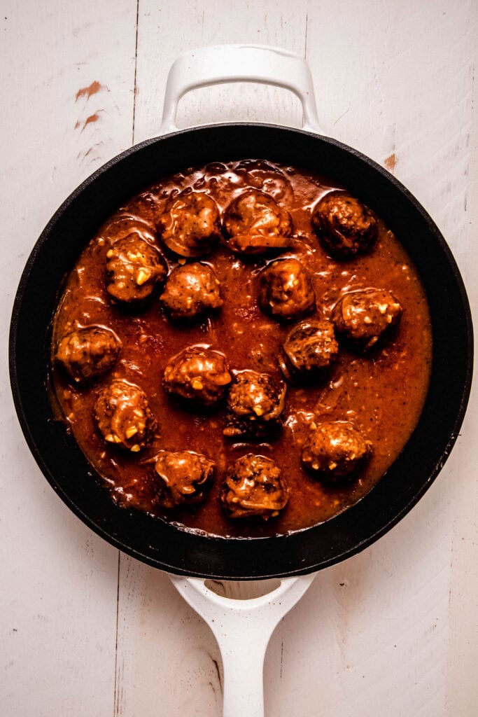 Meatballs in onion gravy in skillet.