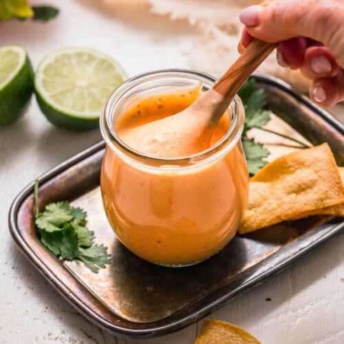 Hand stirring spoon into small jar of southwest ranch dressing.