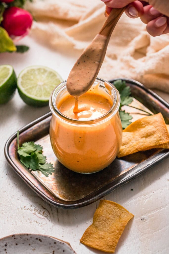 Hand drizzling southwest ranch dressing into small jar.