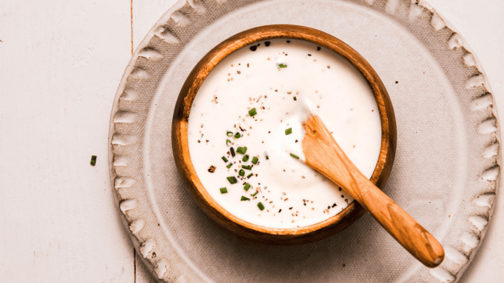 PREPARED CREAMY HORSERADISH SAUCE IN SMALL BOWL WITH WOODEN SPOON.