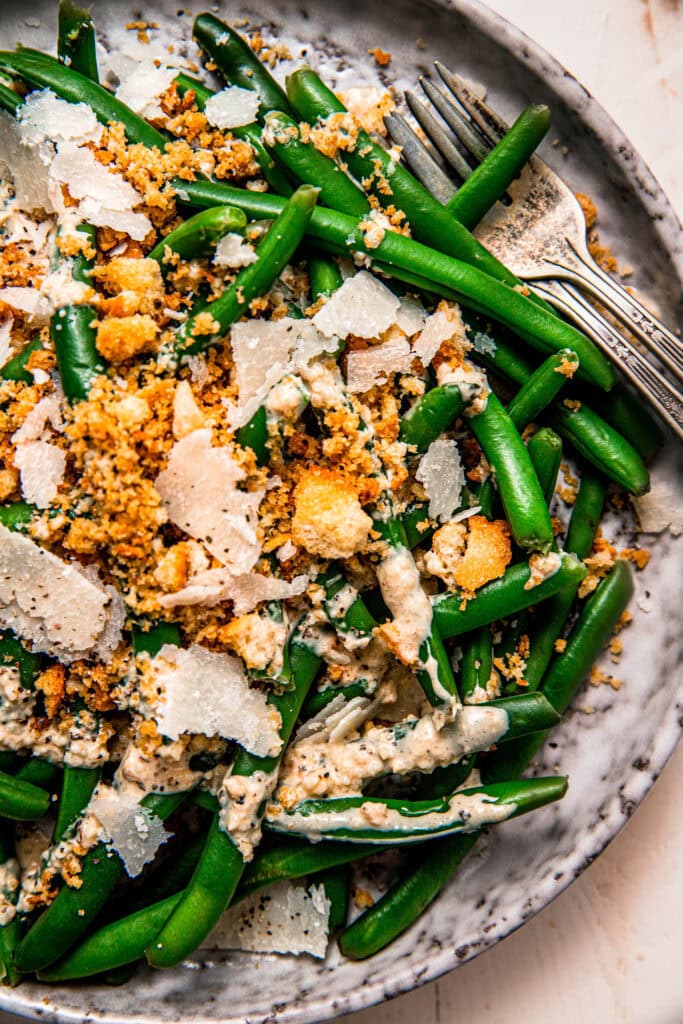 Overhead close up of caesar green beans drizzled with dressing.