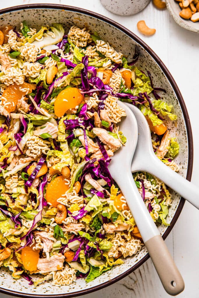 Overhead close up of chinese chicken salad in serving bowl with tongs.