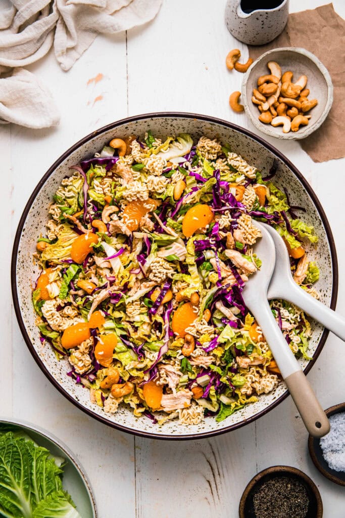 Prepared chinese chicken salad in serving bowl with serving spoons.