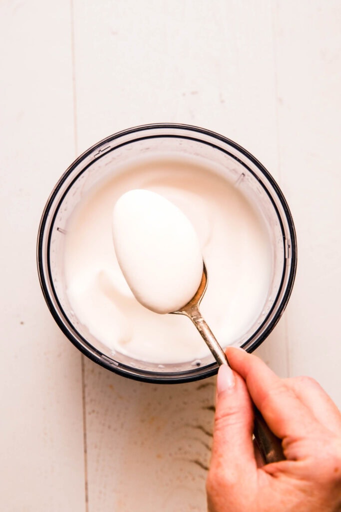 Spoon dipping into bowl of sour cream made from cottage cheese.