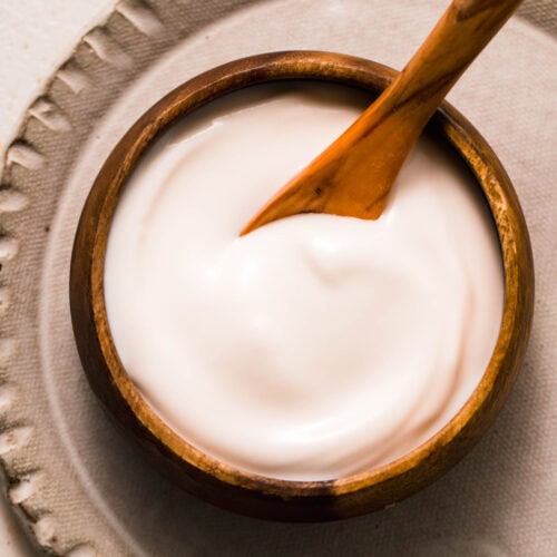 Overhead close up of small wooden bowl filled with sour cream made from cottage cheese.