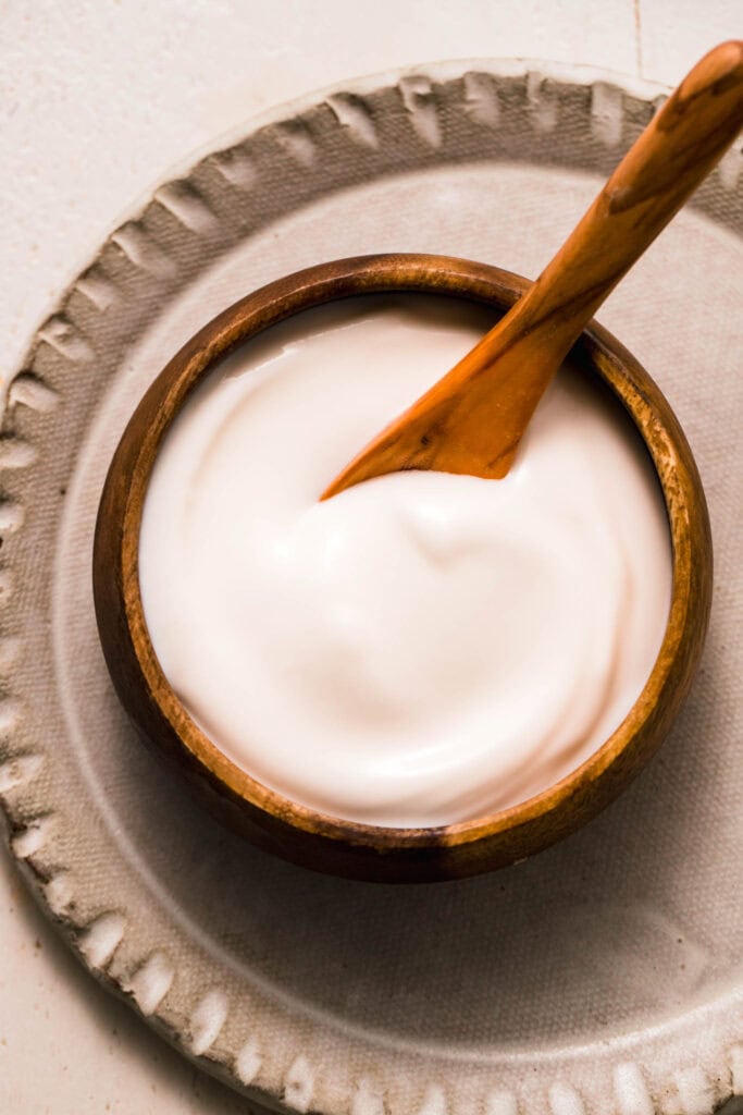 Overhead close up of small wooden bowl filled with sour cream made from cottage cheese.