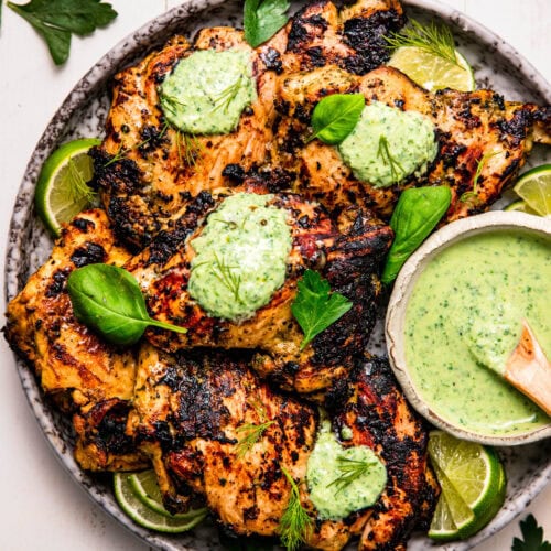 Overhead shot of plate of chicken thighs topped with green goddess sauce.