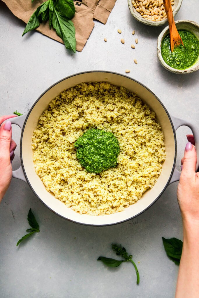 Pot of fluffy cooked quinoa topped with dollop of pesto.
