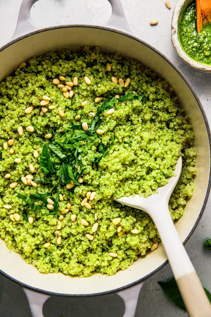Finished pot of pesto quinoa topped with basil leaves and pinenuts.