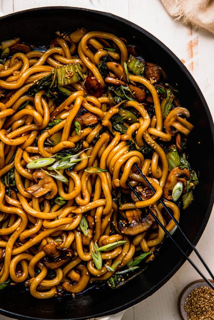 Teriyaki noodles in large skillet swirled with sauce. 