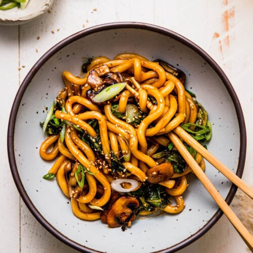 Overehead shot of bowl of teriyaki udon noodles with chopsticks.