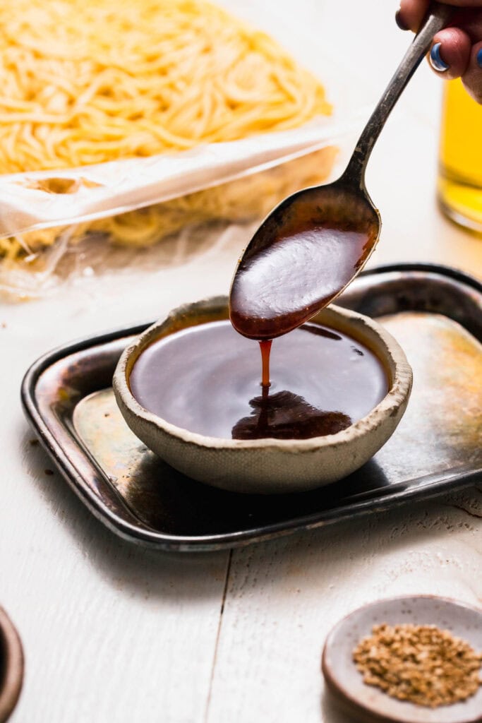 Yakisoba sauce drizzling off of spoon.