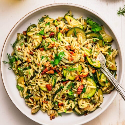 Zucchini orzo pasta salad in serving bowl on white counter.